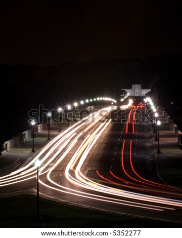 Streaks of automobile headlights and tail lights streak across a bridge in Washington, DC.