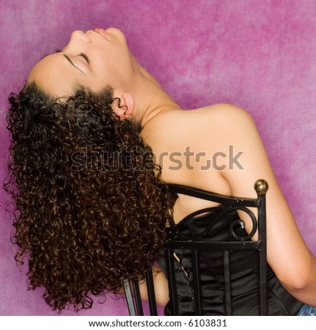 Beautiful, young mixed race woman reclining with eyes closed. Masters canvas purple background and ring flash lighting add fashion look to the image.