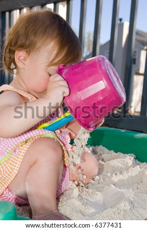 For babies aged one to two, everything is a learning experience. This little girl is curious and busy as she dumps sand in her sandbox.