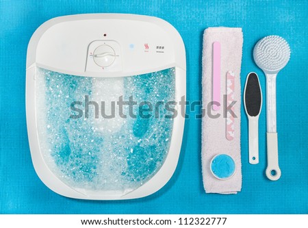 Photo of electric foot spa with bubbles and accessories on a blue rubber mat