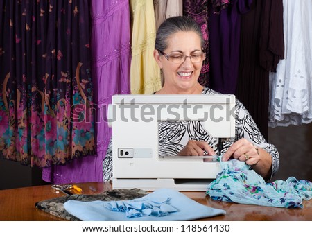 Happy senior woman dressmaking with sewing machine