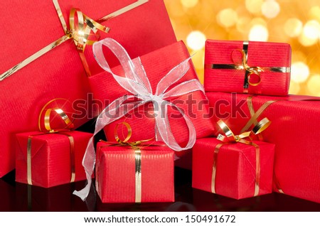 Photo of a collection of red and gold gift boxes with out of focus lights on a golden background