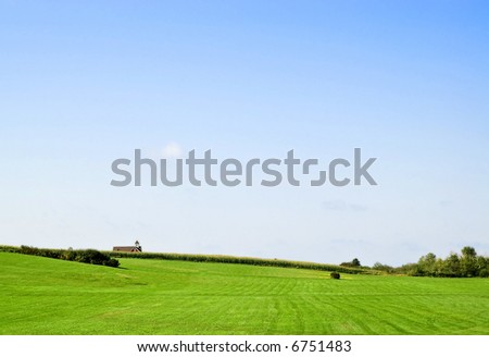 Green field with school-house in distance (Grand Pre, Nova Scotia)