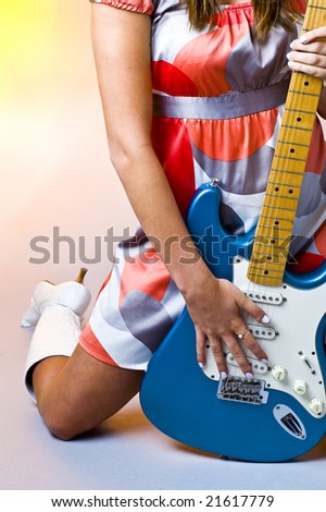 Girl in retro 1960\'s outfit kneels and holds guitar