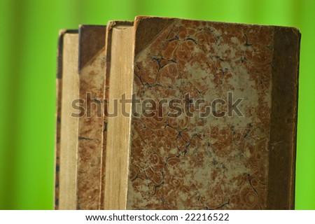 old antique leather books against green background.