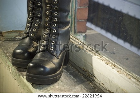 Goth punk knee-high fashion boots standing on old window sill.
