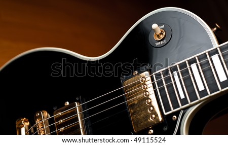 Classic black Les Paul style rock and roll or jazz guitar in soft spotlight. Stage or studio concept ready to perform.