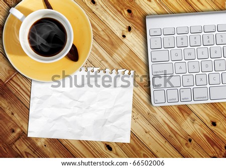blank paper on wood table with computer keyboard and a cub of coffee