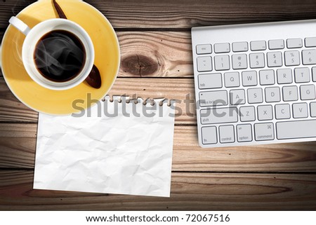 blank paper on wood table with computer keyboard and a cub of coffee