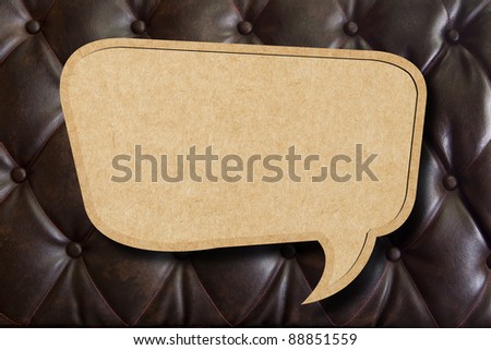 Recycle paper speech bubble on leather upholstery background
