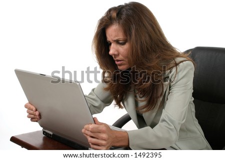 Attractive executive business woman working on a laptop computer frustrated with work.