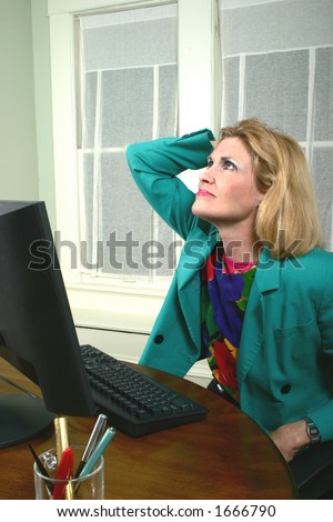 Beautiful executive business woman with a hand on her head thinking at a computer in the office.