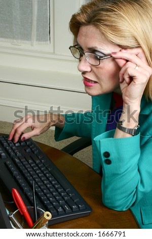 Beautiful business woman wears eyeglasses to look at detail of her work on the office computer.