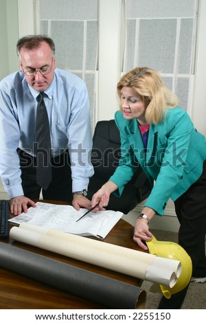 Architect showing client blueprints in the office.  Landscape horizontal orientation.