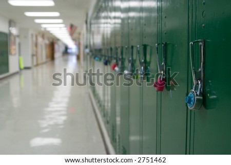 Closeup view of a lock on a school locker with row of lockers and and empty school hallway in background out of focus from depth of field.