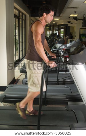 Man working out on a treadmill in a fitness center.  His feet are blurred from the walking motion.