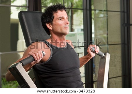 Man exercising his arm muscles on an exercise machine in a fitness center.