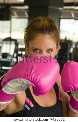 Eyes of beautiful woman looking over hot pink boxing gloves.