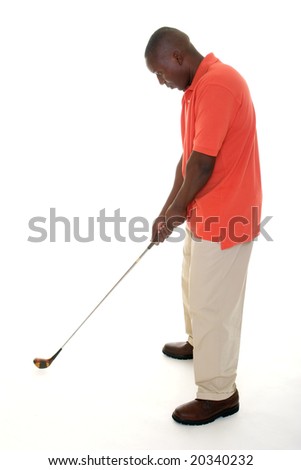 Casual young African American man in a bright orange golf shirt holding a golf club to lining up a drive and preparing to swing.