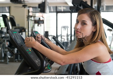 Woman working out on a stationary cycle machine in a fitness club.