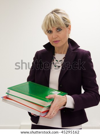 Woman teacher or instructor in a college, university, high school, middle school, elementary classroom holding a small stack of books.
