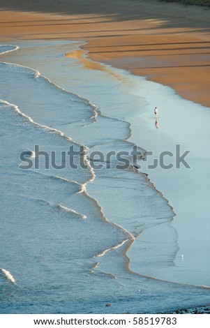 high view of waves on beach with person in the distance