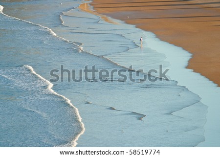 high view of waves on beach with person in the distance