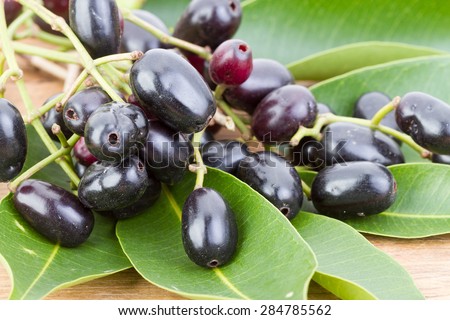 Jambolan plum or Java plum with grean leaves on wooden plate scientific name is \'Syzygium cumini (L) Skeels.\'