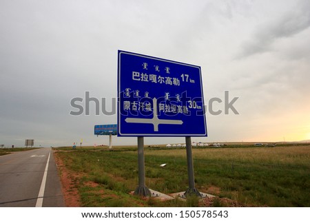 Road sign in lonely Inner Mongolia.  The road sign only in Mongolian and Chinese, showing North is Bala Gell Gawler Town and East is Alatangaole township.