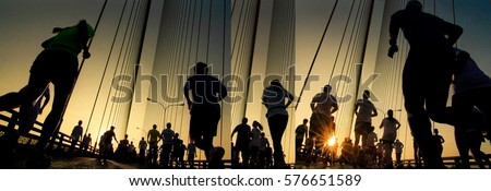 Silhouette of athletes running marathon with strong back light at summer sunrise
