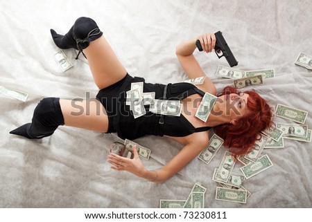sexy young red-haired woman with gun and money