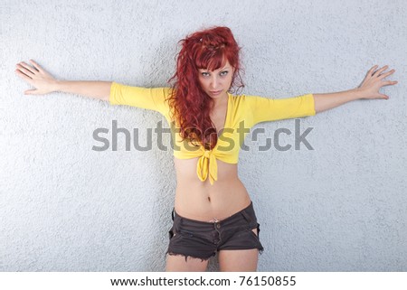 portrait of sexy young red-haired woman in yellow blouse and black shorts