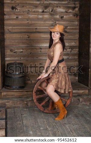 CowGirl with a ancient cart wheel standing in old depot