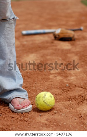 A young woman wear flip flops in the infield dirt.