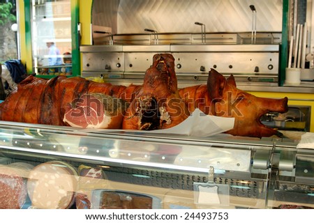 A cooked pig and pig\'s head for sale in a european meat and cheese market in Italy.