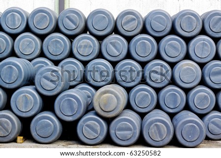 Big pile of gray plastic barrels in factory