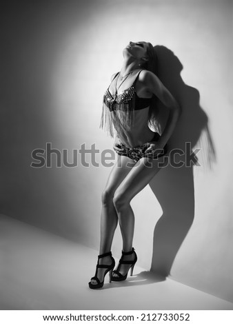 The beautiful neat figure woman on heels and in a suit in rock style poses in the studio