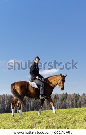 Young man horseriding in the fields by the countryside