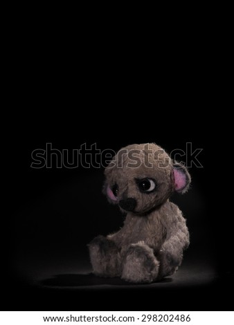 Sad little bear sitting alone at a black background
