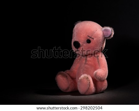 Cute little pink teddy bear stuffed animal at a black background