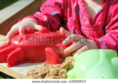 small girl playing in sandpit in the summer sun