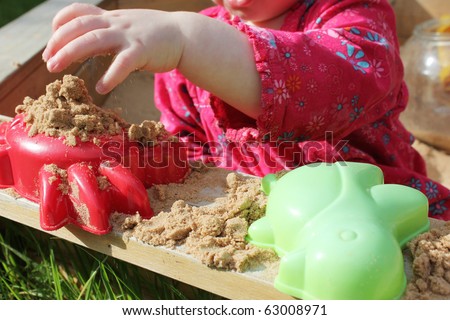 small girl playing in a sandpit in the summer sun