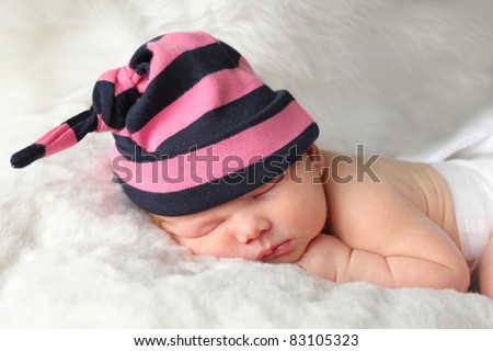 Tiny newborn baby lying on fur blanket asleep