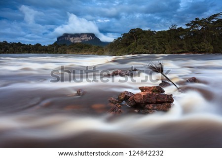 Rainy Season in the Venezuelan Jungle. Strong current of the river in the foreground with Tepui (mountain) in the background. Wild and clean green environment.