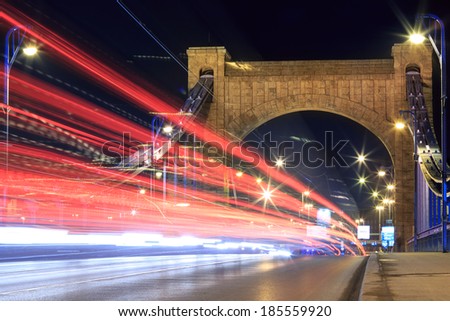 High traffic lights on ancient bridge with city lights all in the middle of the action