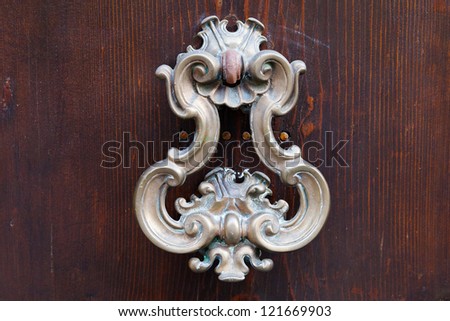 old bronze door handle on dark brown wooden urban door