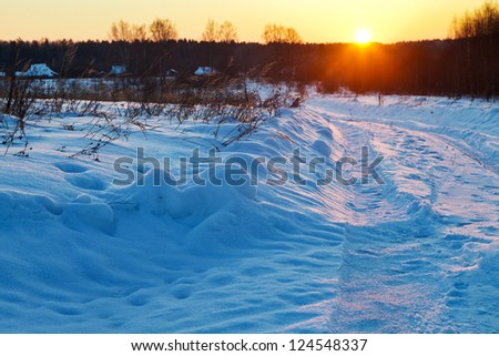sunset under blue winter snowdrifts on country road