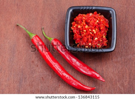 pods of red hot pepper and spicy sauce on wooden table