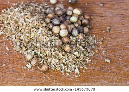 milled coriander spice and dried coriander seeds on wooden board