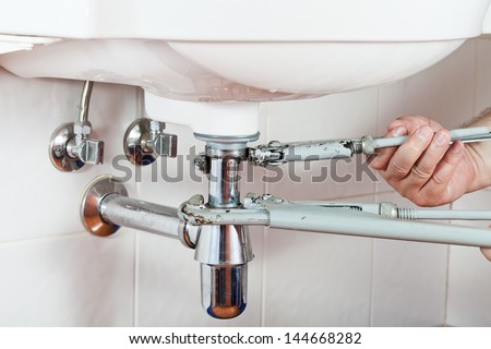 plumber repairing sink drain by pipe-wrenches